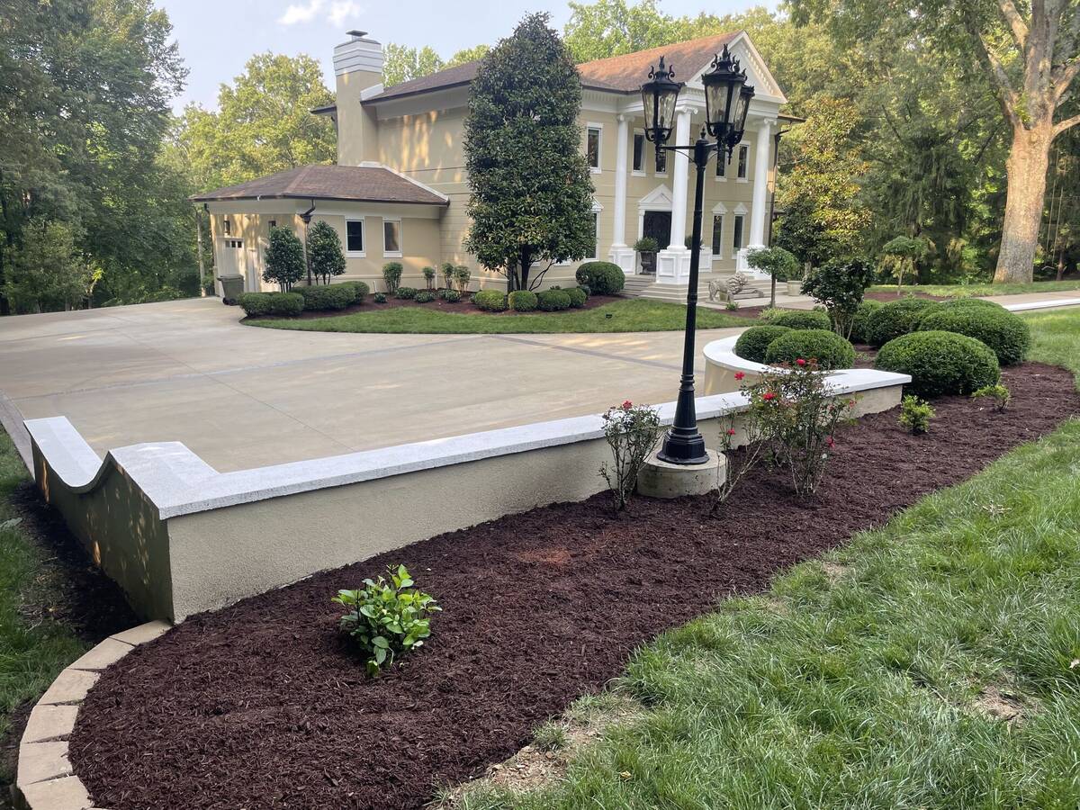 Stone retaining wall with lamppost and mulched bed